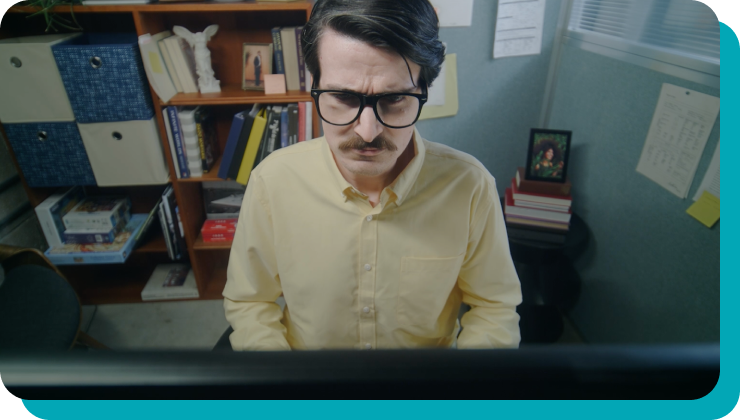 a man with glasses and a mustache in a yellow button down scowling at his computer