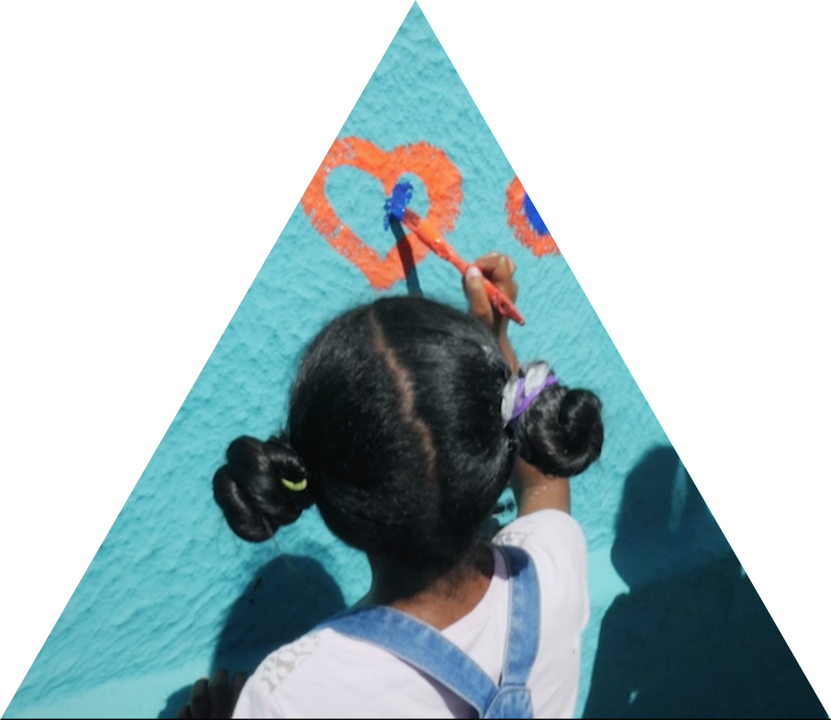 a young girl with overalls and her hair in two buns in painting a heart on a wall