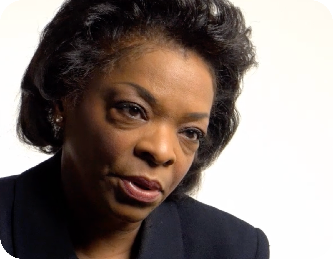 a black woman in business attire speaking to the camera