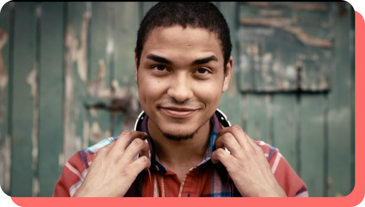 a young african american man smiling with a set of over-hear headphones on his shoulders