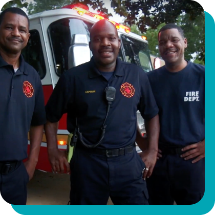 Three uniformed African American EMTs standing in front of an ambulance