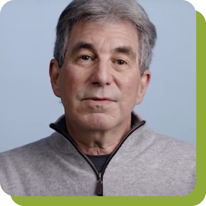 a white man with grey hair wearing a grey zip-up sweater