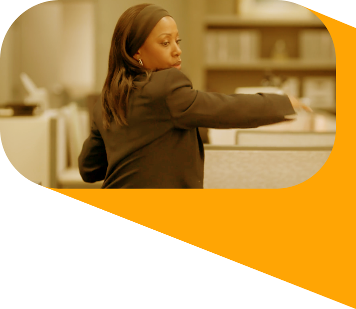 A black woman in a dark suit reaching her arm across her body