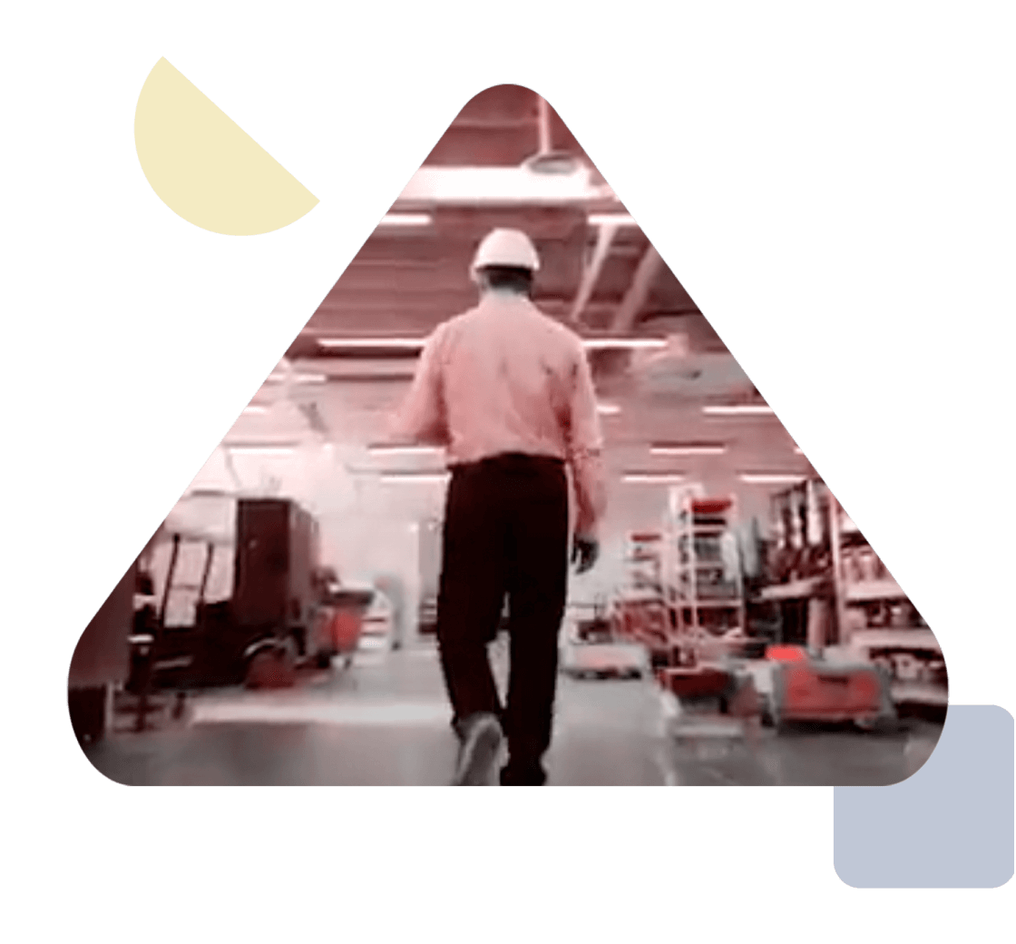 a man wearing business attire and a hard hat walks through a warehouse